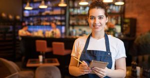 Young smiling waitress in workwear standing in luxurious restaurant
